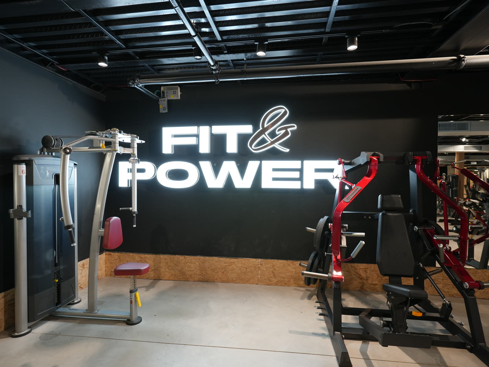 מכשירי הכוח במתחם הגברים, על רקע לוגו fit and power מואר